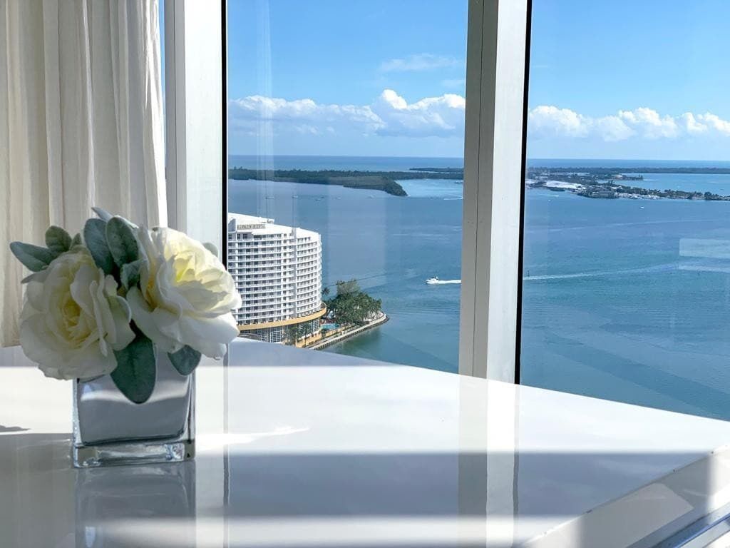 Vista desde una ventana sobre un cuerpo de agua, con un edificio grande y un muelle.