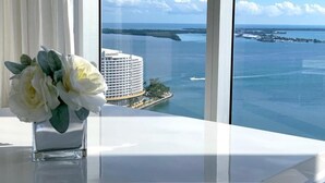 A view from a window overlooking a body of water with a large building and a dock. - Icon Brickell Condo with Bay Views (Miami)