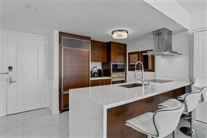 A modern kitchen with a central island, stainless steel appliances, and a chandelier. - Icon Brickell W Hotel | Skyline View 1BR Suite (Miami)
