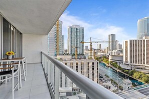 A balcony with a view of a cityscape, including high-rise buildings and a river. - Icon Brickell W Hotel | Skyline View 1BR Suite (Miami)