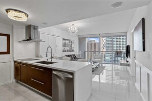 A modern kitchen with a central island, stainless steel appliances, and a chandelier. - Icon Brickell W Hotel | Skyline View 1BR Suite (Miami)