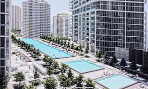 A high-rise building with a rooftop swimming pool surrounded by lounge areas and trees.