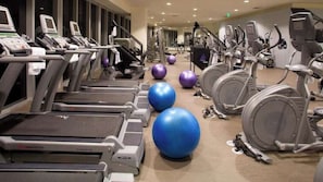 A gym with treadmills, elliptical machines, and exercise balls.