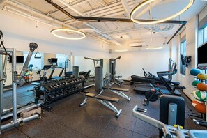 Un gimnasio con equipo de ejercicio, espejos y una variedad de pesas.