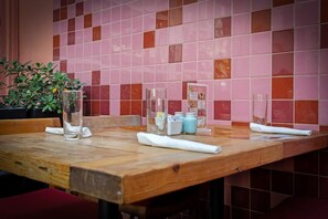 Una mesa de restaurante con un muro de azulejos al fondo.