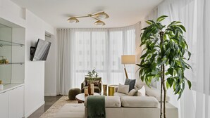 Una sala de estar moderna con un sofá, una mesa de centro, una lámpara y una planta grande.