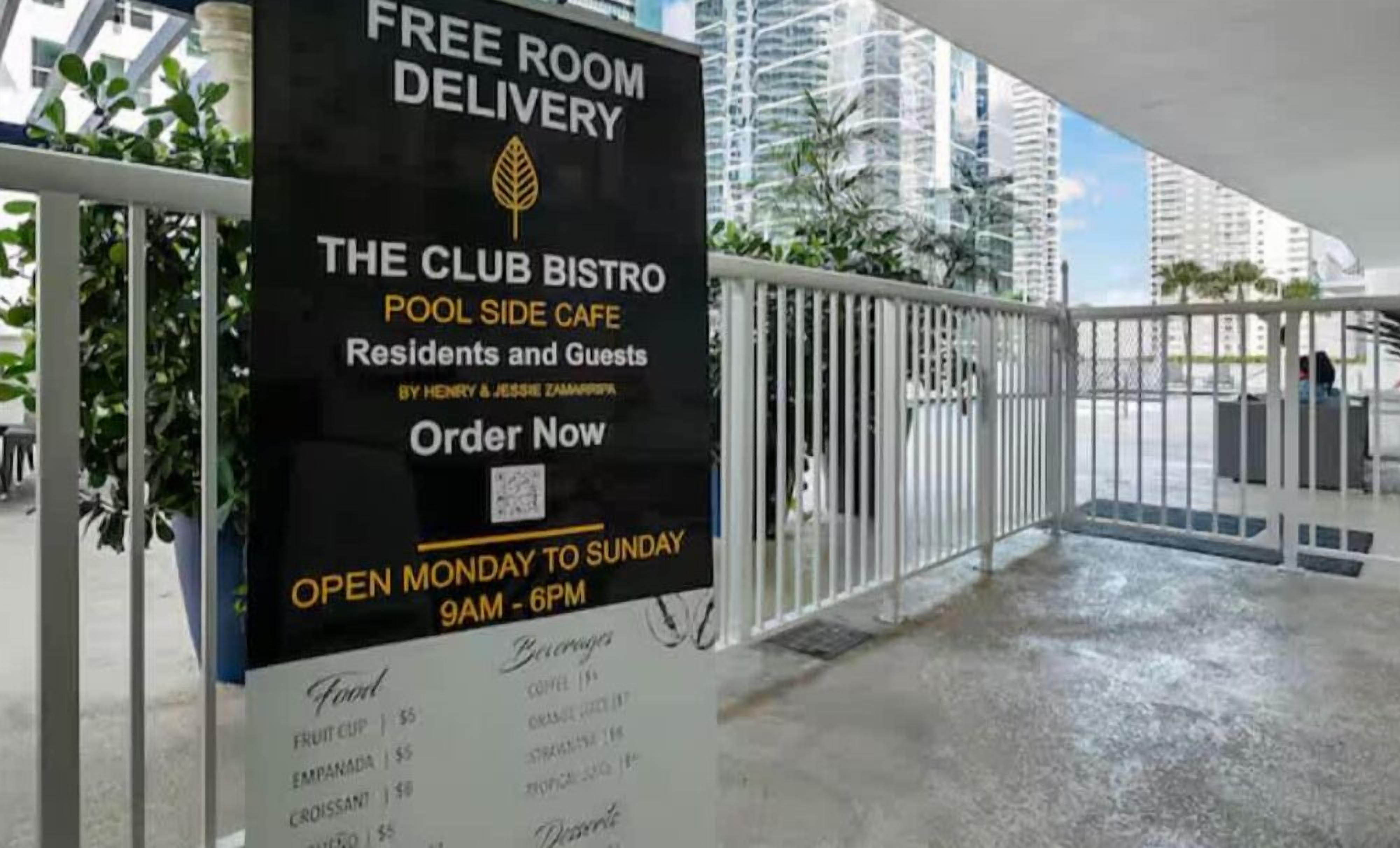 A sign for 'The Club Bistro' with a menu listing items like fruit cup and croissant.