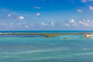 An aerial view of a coastal area with clear waters, a small island, and a distant shoreline. - Brickell Apt with Dual Views, Pool, free Parking (Miami)