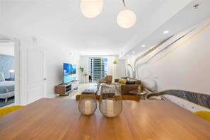 Una sala de estar moderna con una mesa de comedor de madera, dos candelabros esféricos, un sofá y un televisor.