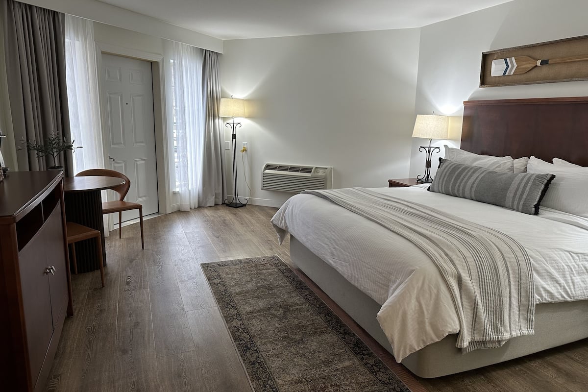 A bedroom with a bed, bedside tables, a desk, chair, and a floor lamp.