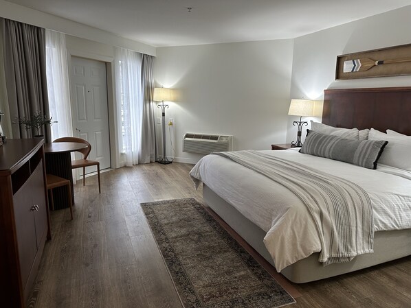 A bedroom with a bed, bedside tables, a desk, chair, and a floor lamp.