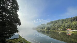 A serene lakeside view with a clear sky, a dock, and a row of houses along the water's edge. - Foxburg Inn (Foxburg)
