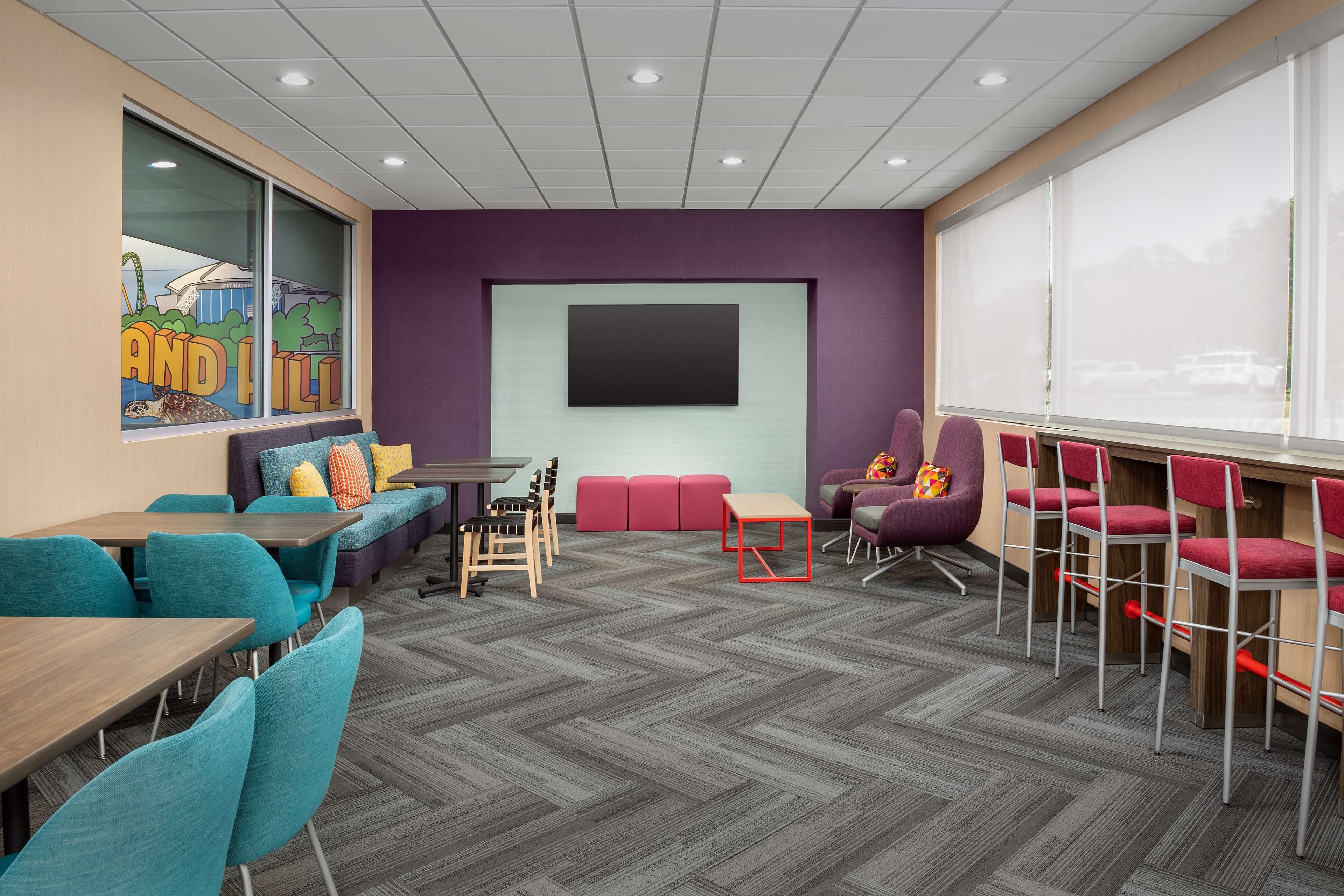 A conference room with a large screen, seating arrangements, and a herringbone patterned floor.