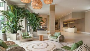 A spacious lobby with wicker furniture, large potted plants, and a central spiral rug. - Embassy Suites by Hilton Panama City Beach Resort (Panama City Beach)