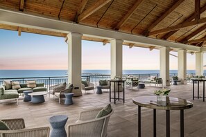Espaço coberto ao ar livre com assentos e vista para o oceano.