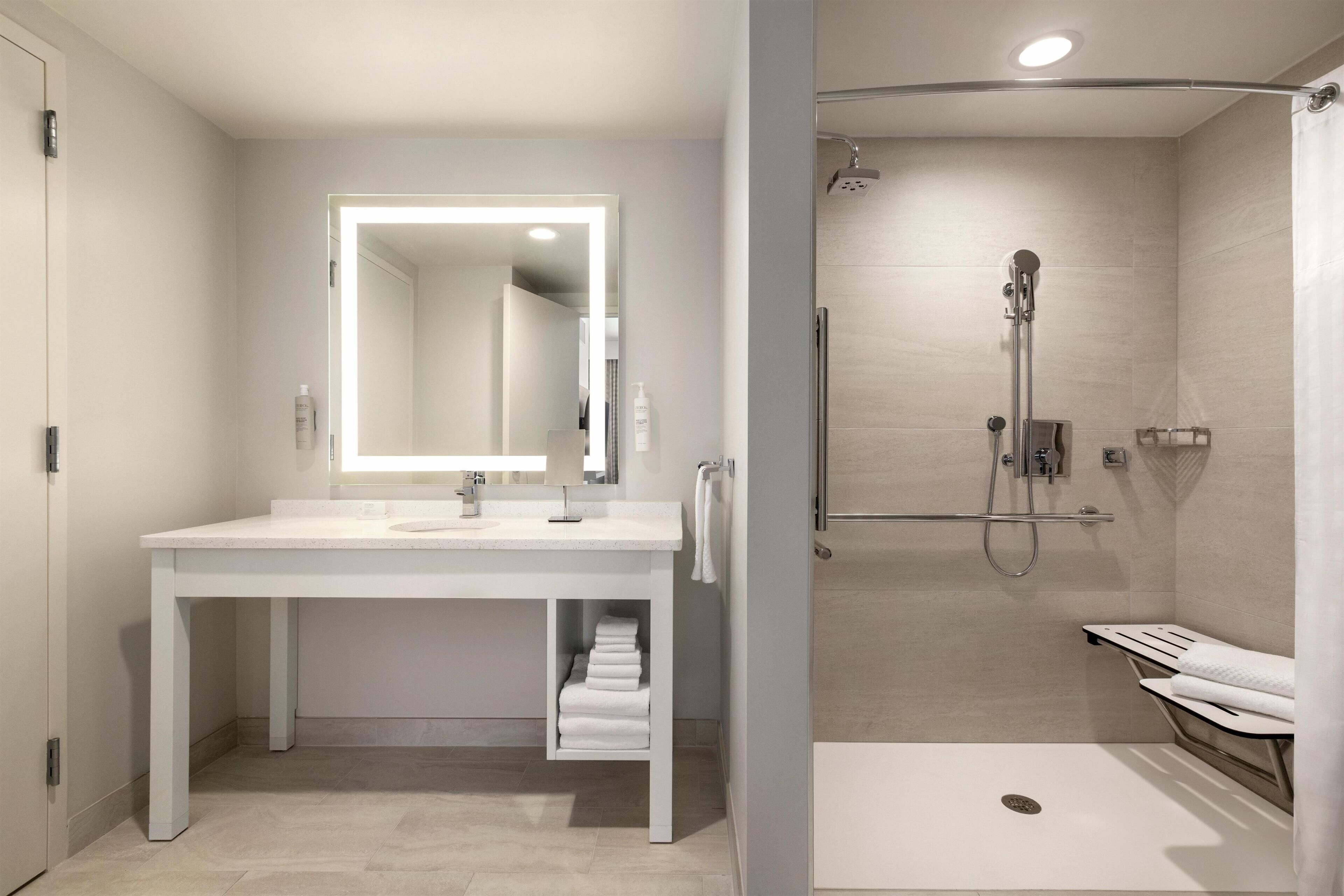 A modern bathroom with a white vanity, a large mirror, and a separate shower area.