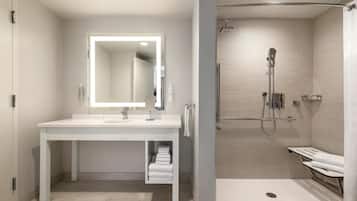 A modern bathroom with a white vanity, a large mirror, and a separate shower area.