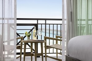 A balcony with a table, two chairs, a bottle, and two glasses.