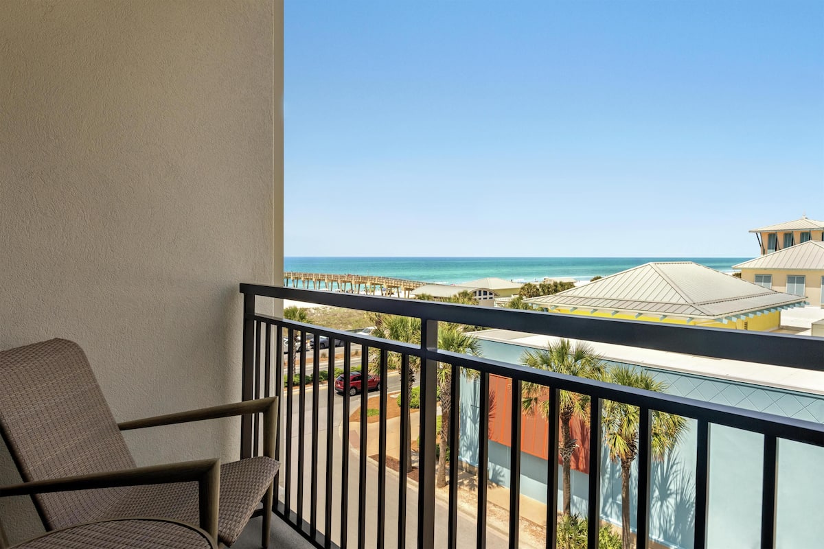 A balcony with a view of the beach and ocean.