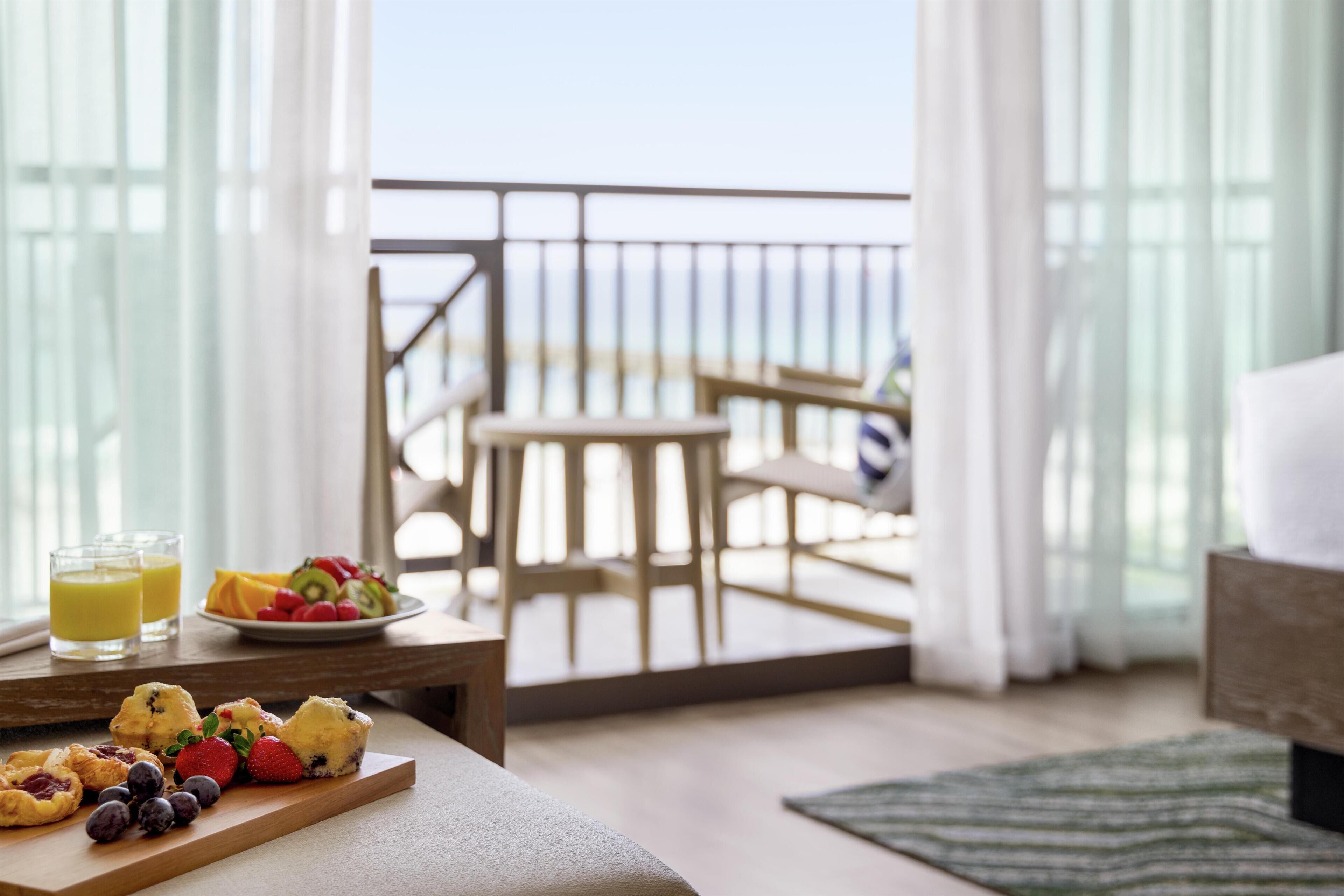 Een balkon met een houten tafel, een stoel en uitzicht op zee.
