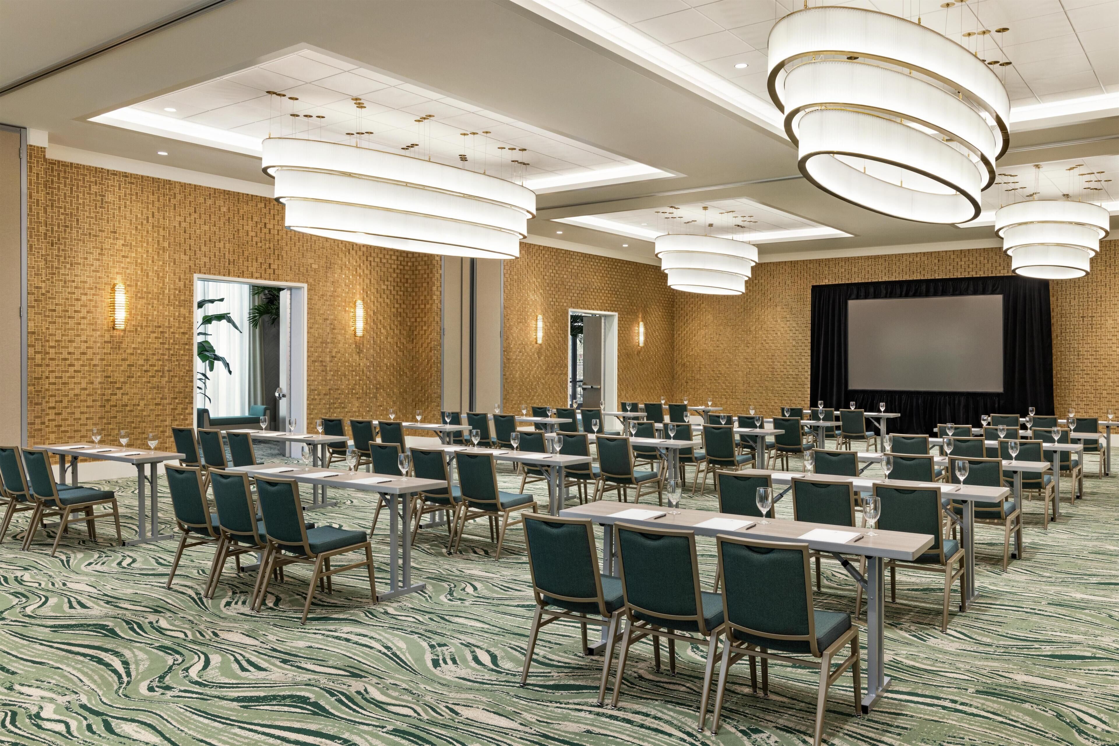 Une salle de conférence équipée de plusieurs tables et chaises, d’un grand écran et d’un système d’éclairage moderne.