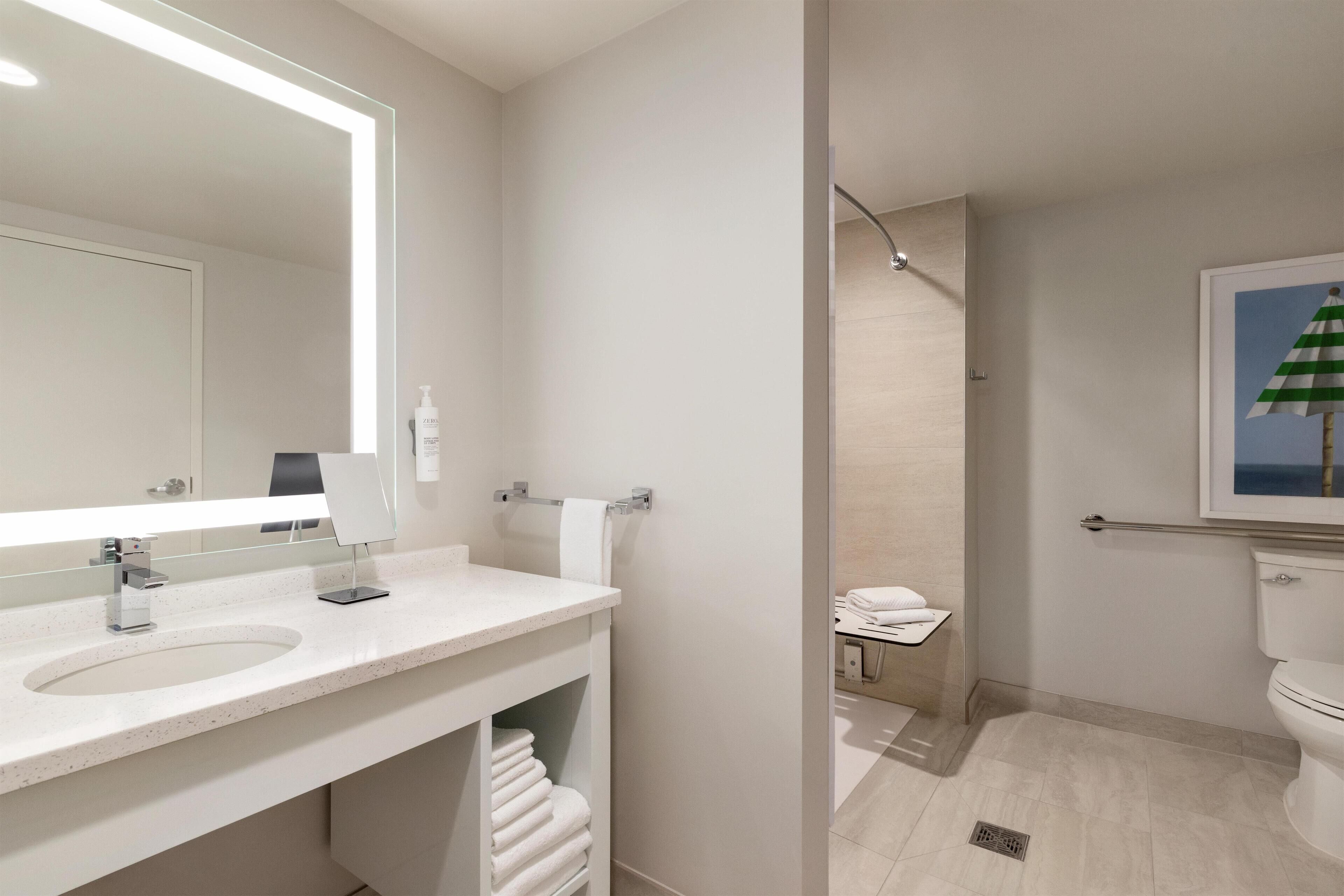 Un baño moderno con un espejo grande, un lavamanos y un inodoro.