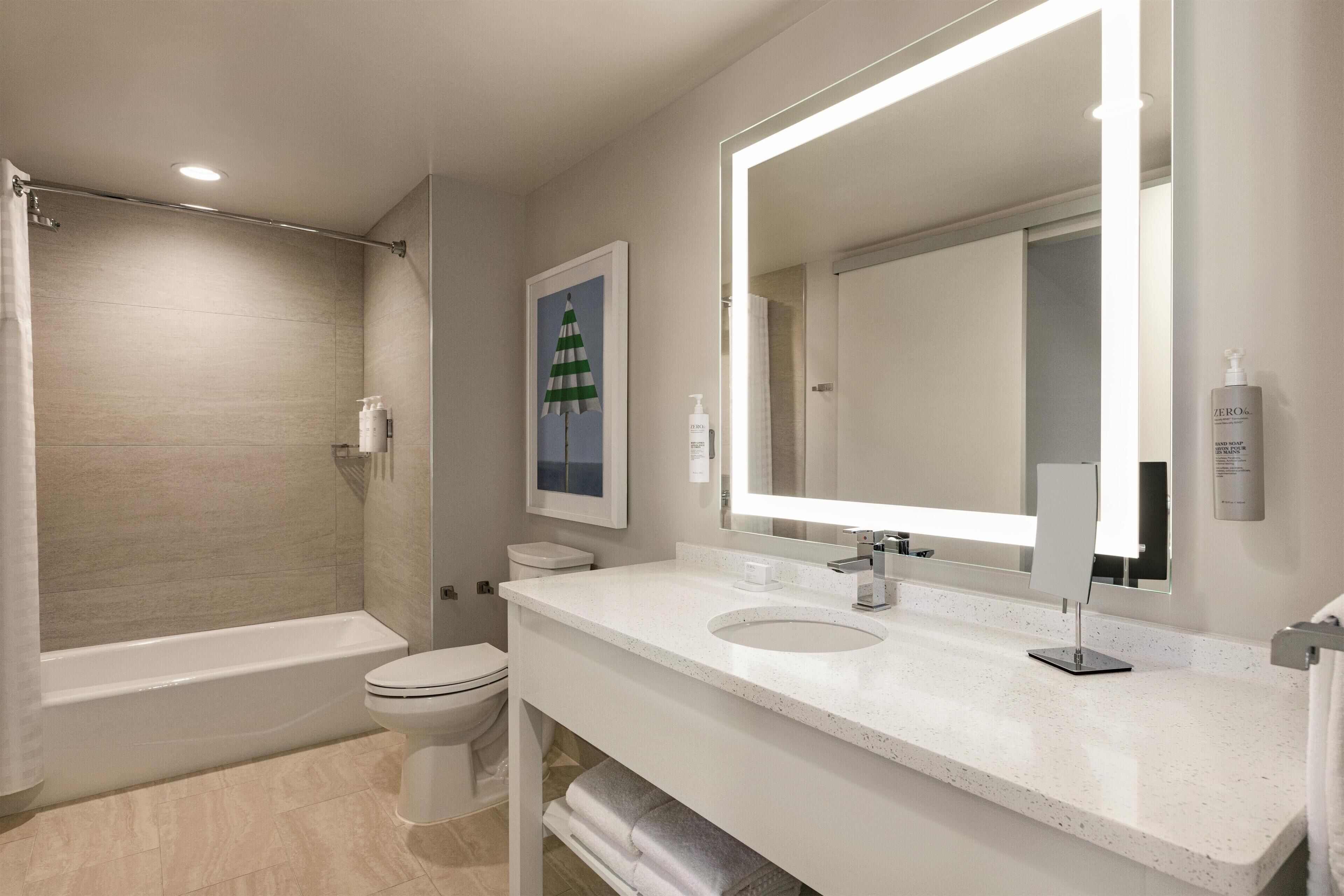 Un bagno moderno con vasca, servizi igienici e un mobile vanità dotato di un ampio specchio.