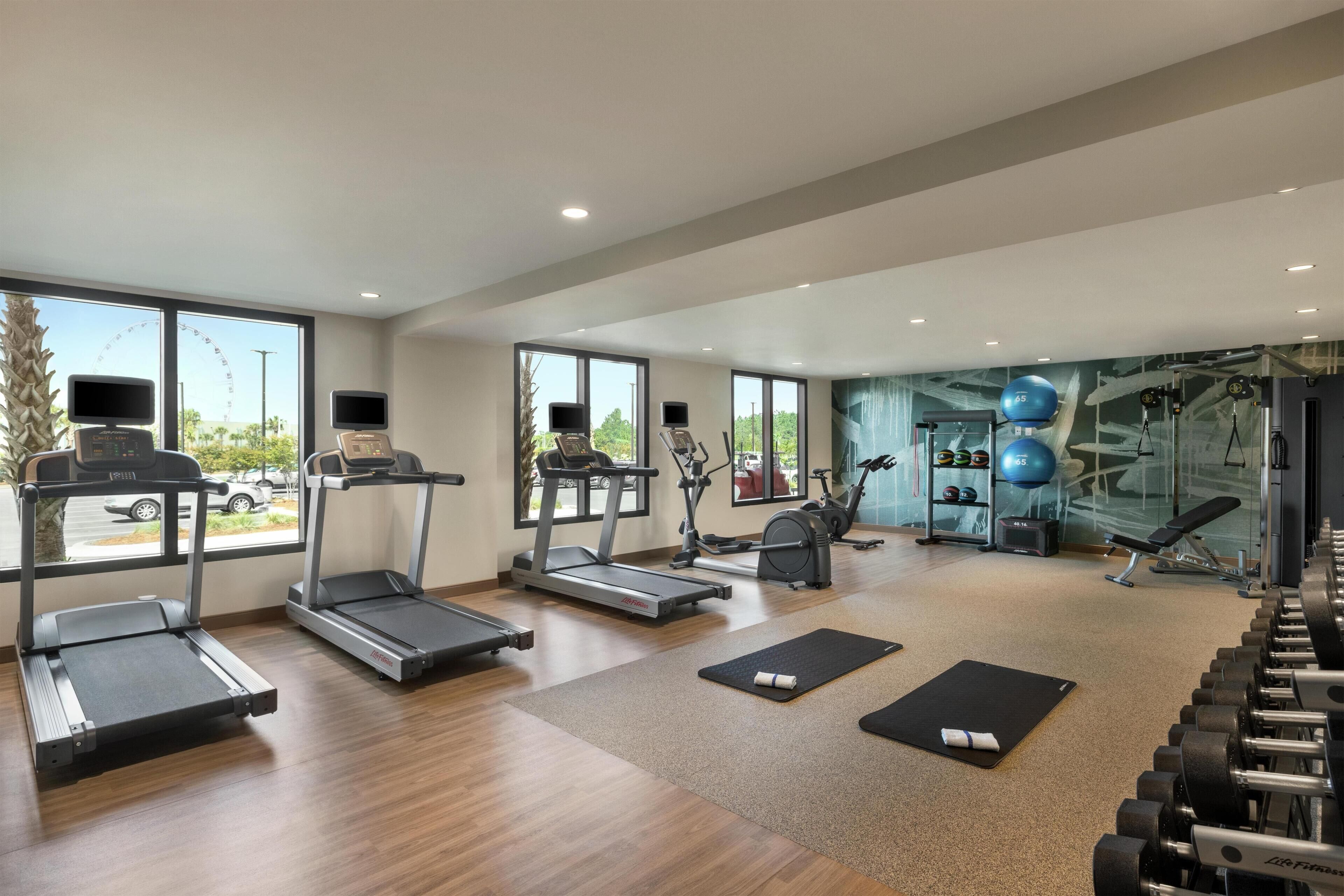 A spacious gym with treadmills, elliptical machines, and free weights.