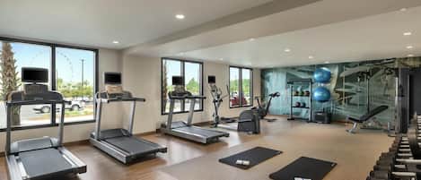 Un gimnasio amplio con cintas de correr, elípticas y pesas libres.
