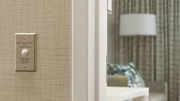A door with an audio-visual alert system for the hearing impaired, a white wall, and a lamp in the background.
