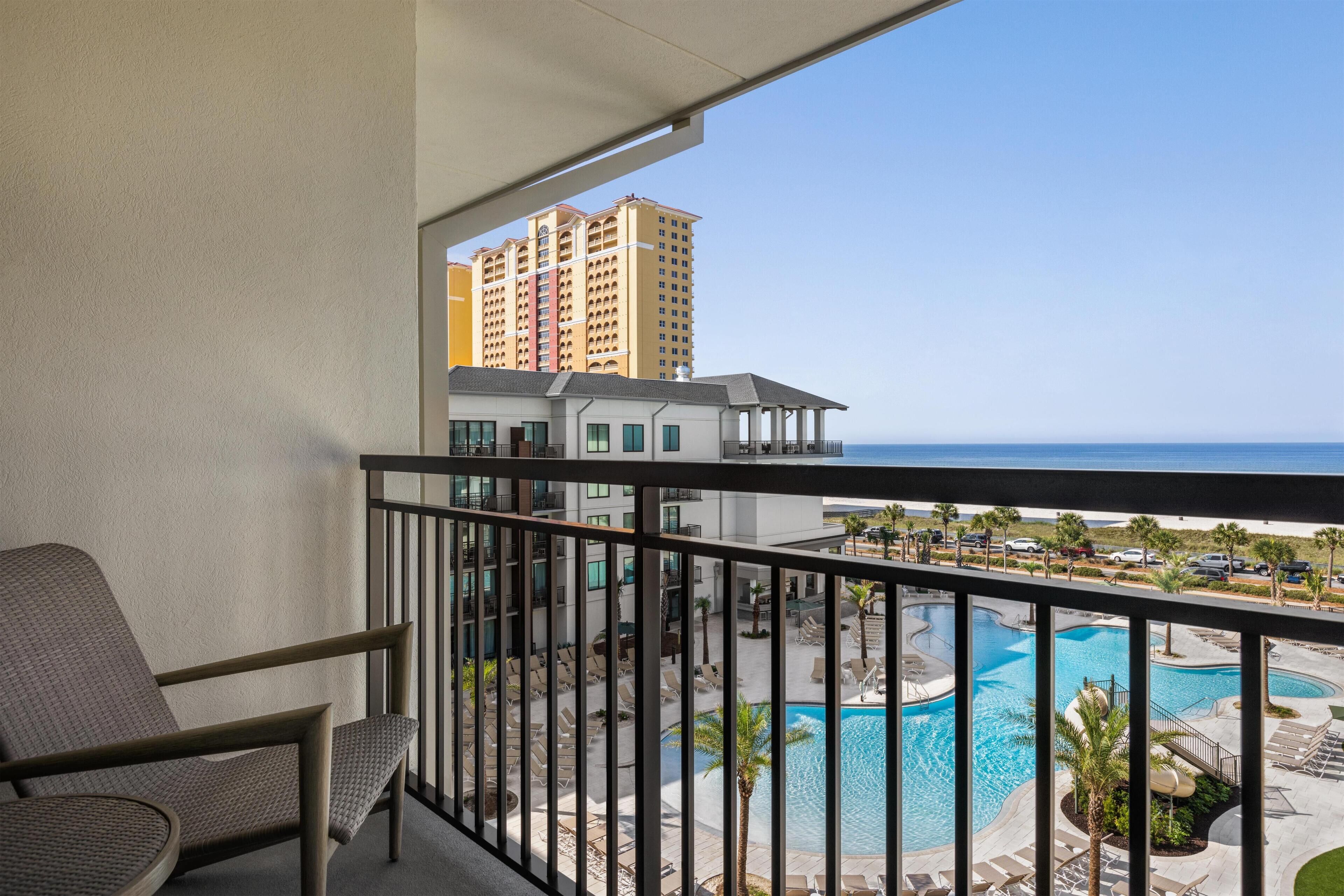 A balcony with a view of a swimming pool and a high-rise building.