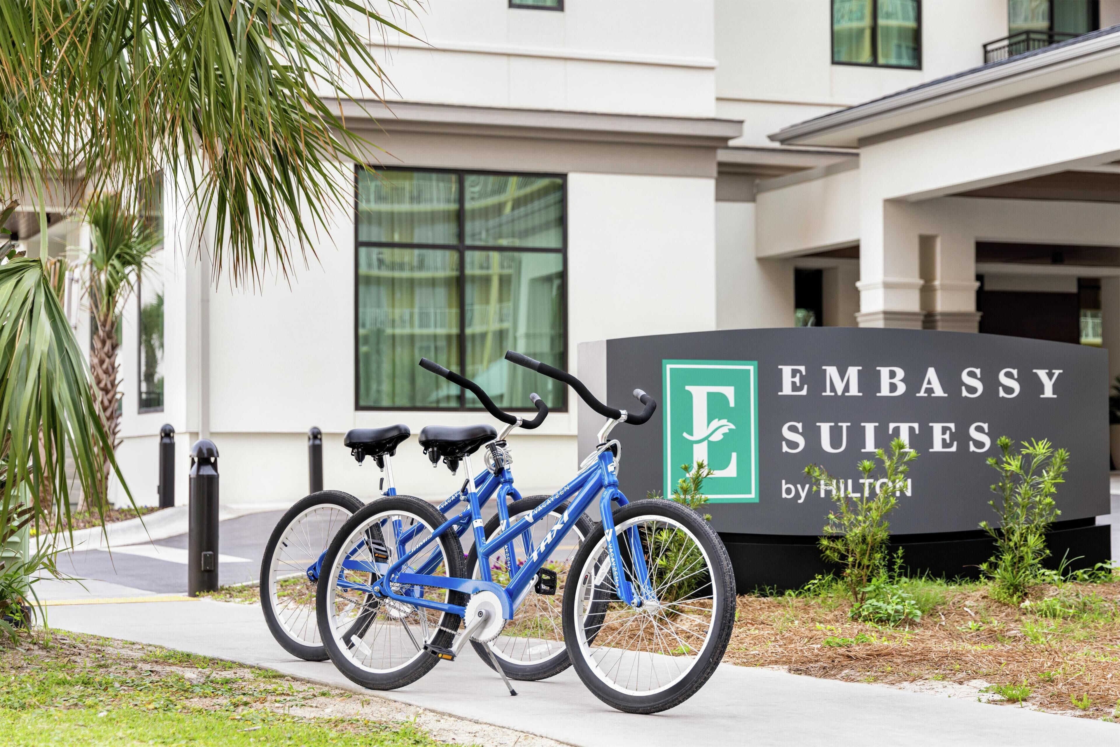 Señal de Embassy Suites by Hilton con una bicicleta azul estacionada al frente.
