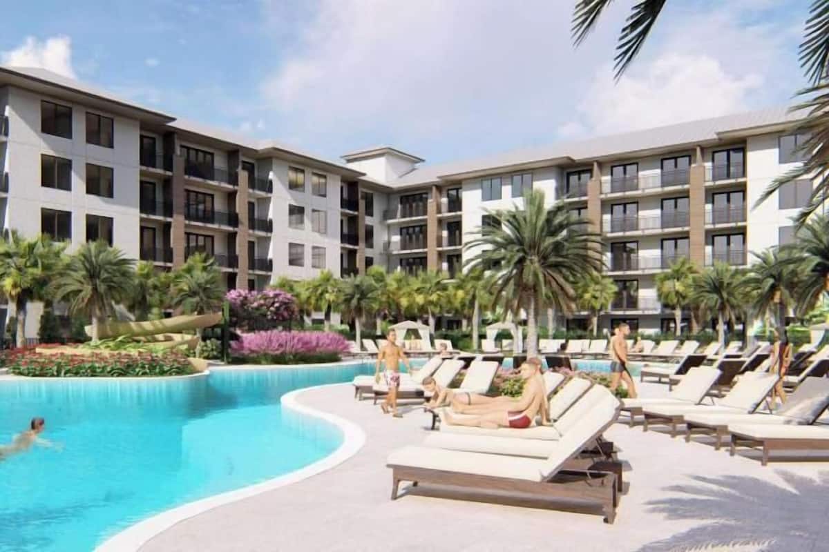 A swimming pool with lounge chairs and palm trees.