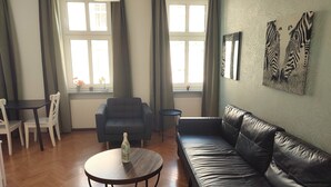 Una sala de estar con un sofá de cuero, una mesa redonda, un sillón negro y un comedor con mesa y sillas.