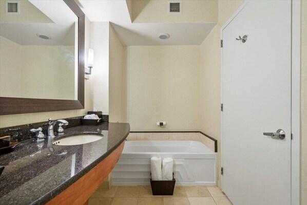 Un baño con lavamanos doble, un espejo, una bañera y una puerta.