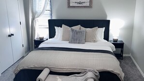 A bedroom with a bed, a ceiling fan, a bedside table with a lamp, a window with curtains, and a wall-mounted picture. - New Remodel 3BD/2Bath Weekly/Monthly Discounts available (Enid)