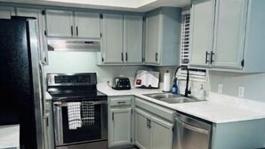 A kitchen with light blue cabinets, a black refrigerator, a stove, and a sink. - New Remodel 3BD/2Bath Weekly/Monthly Discounts available (Enid)