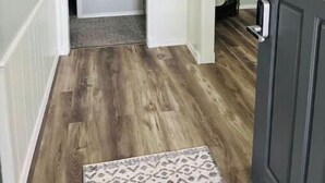 A hallway with wooden flooring, a dark door, and a light fixture above. - New Remodel 3BD/2Bath Weekly/Monthly Discounts available (Enid)