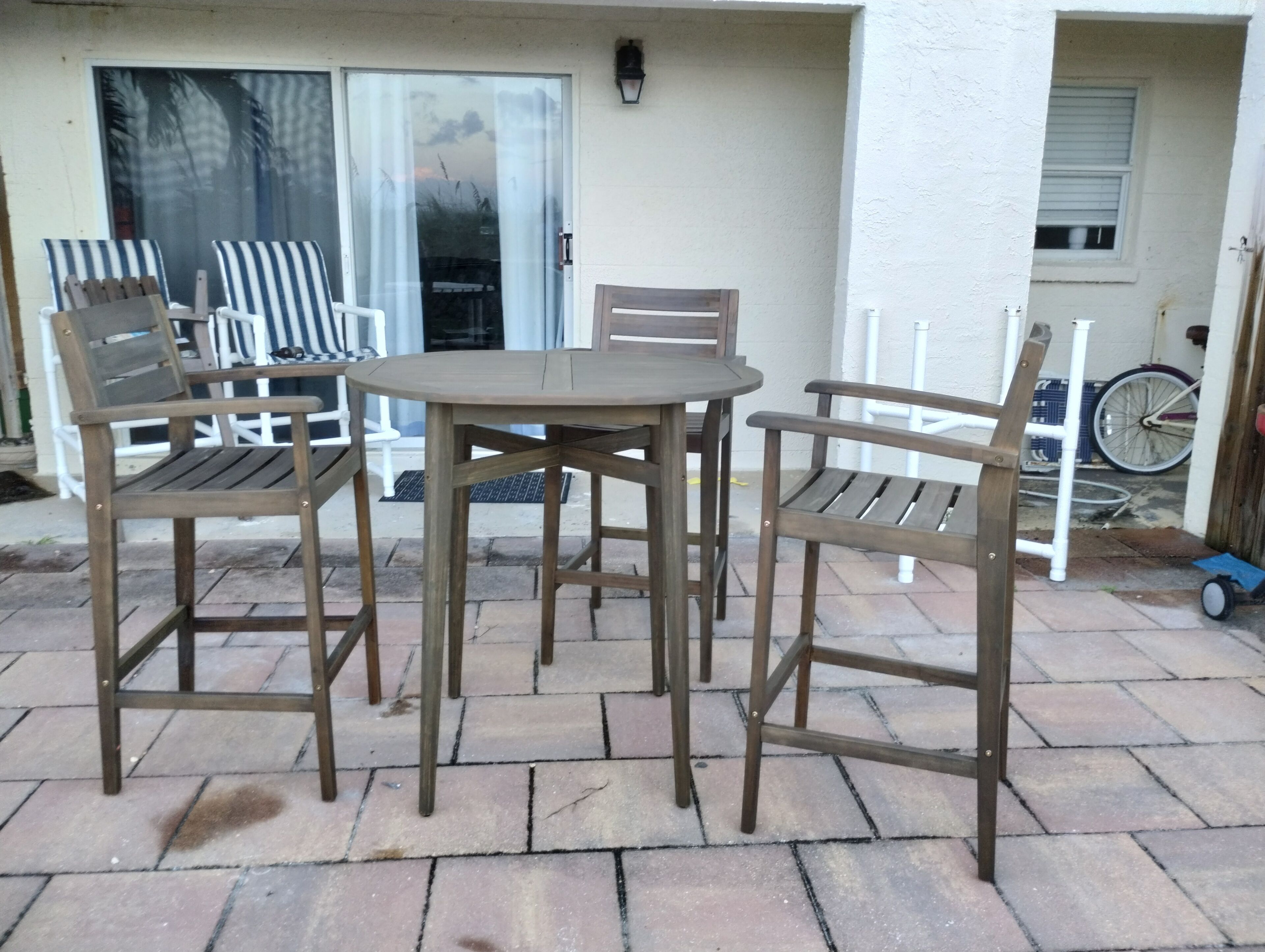 An outdoor patio with a round table and four wooden chairs.