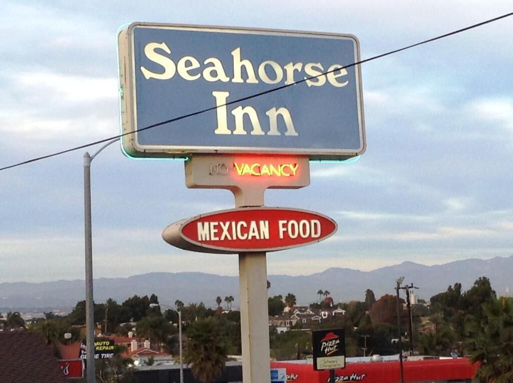 A sign for Seahorse Inn with a vacancy indicator and a sign for Mexican food.