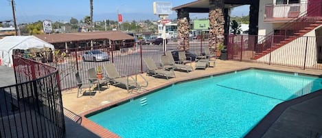 A swimming pool with lounge chairs and a fenced area, a Seacoast Inn sign, and a Taco Bell sign in the background.