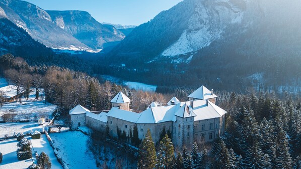 A historic castle with multiple towers, surrounded by snow-covered trees and mountains. - Château de Thorens (Fillière)