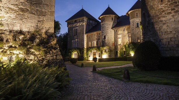 A historic stone building with multiple towers and a cobblestone pathway leading to the entrance. - Château de Thorens (Fillière)