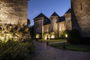 A historic stone building with multiple towers and a cobblestone pathway leading to the entrance.