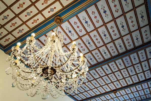 A chandelier with multiple light bulbs hanging from a ceiling with a decorative pattern.