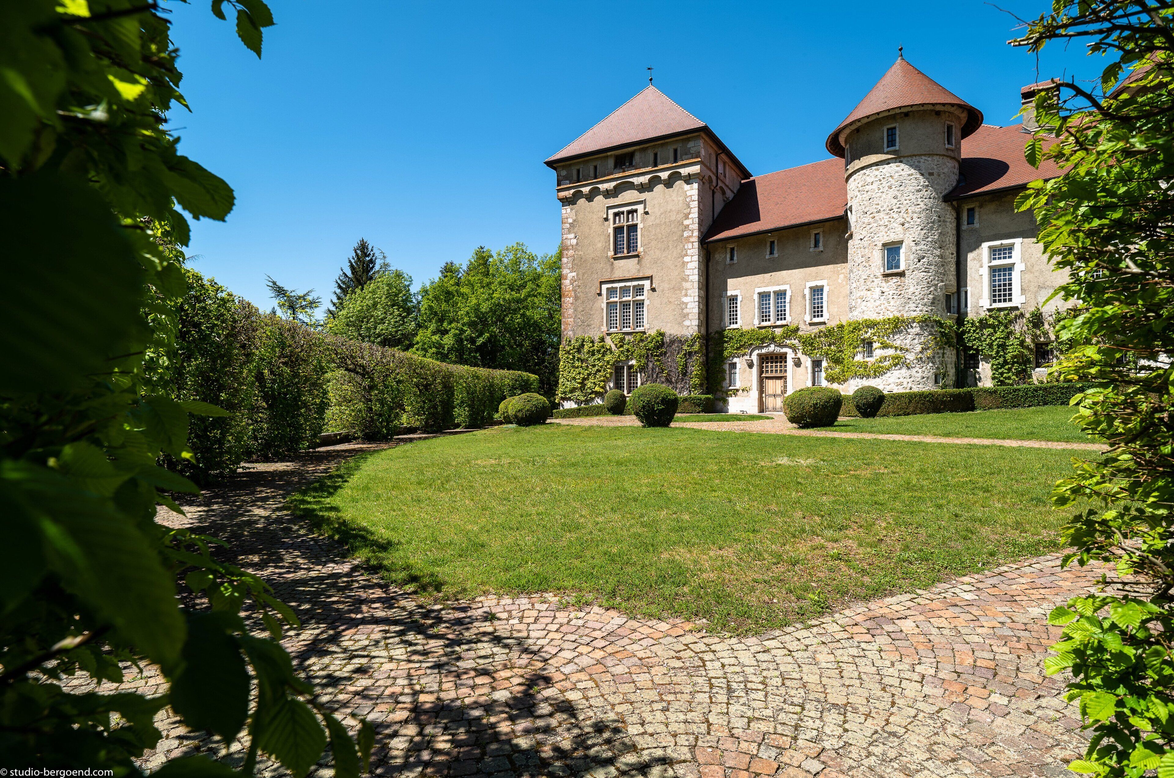 Un château doté d’une tour centrale, d’une cour pavée et d’un jardin bien entretenu.