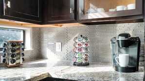 Uma cozinha com cafeteira, porta-xícaras e espaço para temperos.