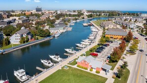 Una marina con barcos amarrados a lo largo de un río, rodeada de edificios residenciales y una carretera.