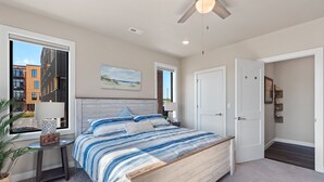 Un dormitorio moderno con una cama grande, un ventilador de techo y vistas a edificios.