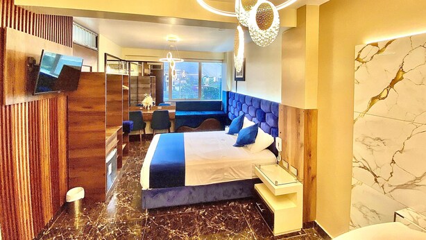 A modern hotel room with a large bed, a desk, and a seating area. - Hotel BlueThree Chancay (Chancay)